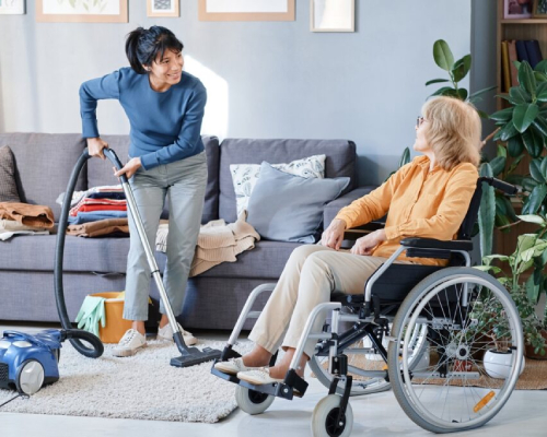 NDIS House Cleaning Services Campbellfield – professional cleaner vacuuming living room for NDIS participant in wheelchair