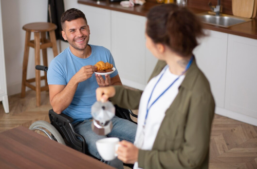 Disability support worker providing meal assistance to a wheelchair user at home