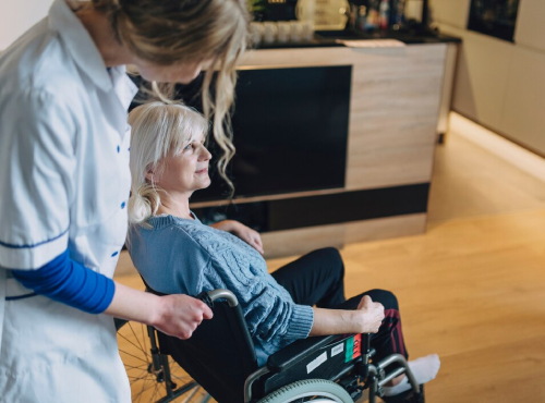 Personal care worker assisting a woman using a wheelchair with mobility and daily living