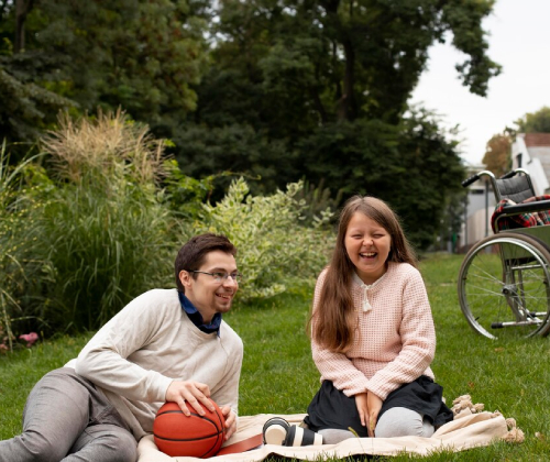 Disability support worker encouraging a child with a disability to participate in outdoor recreational activities