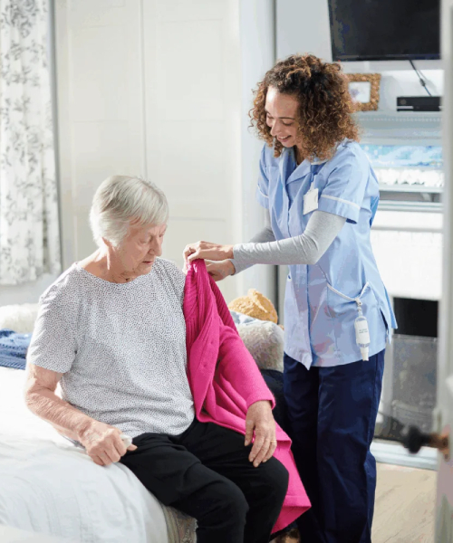 Caring support worker assisting elderly woman with dressing as part of NDIS Personal Care Support Campbellfield and In-Home Personal Care Services.